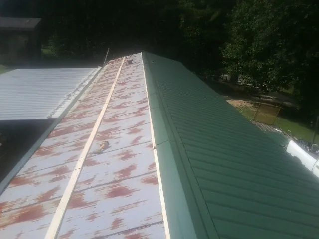 Old rusted panels beside newly installed green metal roofing — Wind Damage Roof Repair by Roofing Brothers in Mount Sterling