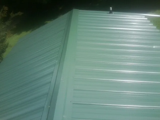 New green metal panels meeting at the ridge of a roof — Flat Roof Repair work by our crew in Mount Sterling