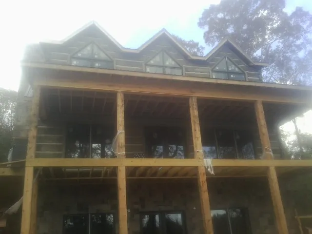 Dormers and porch framing on a large log home under construction — Roof Coating work by our crew in Mount Sterling