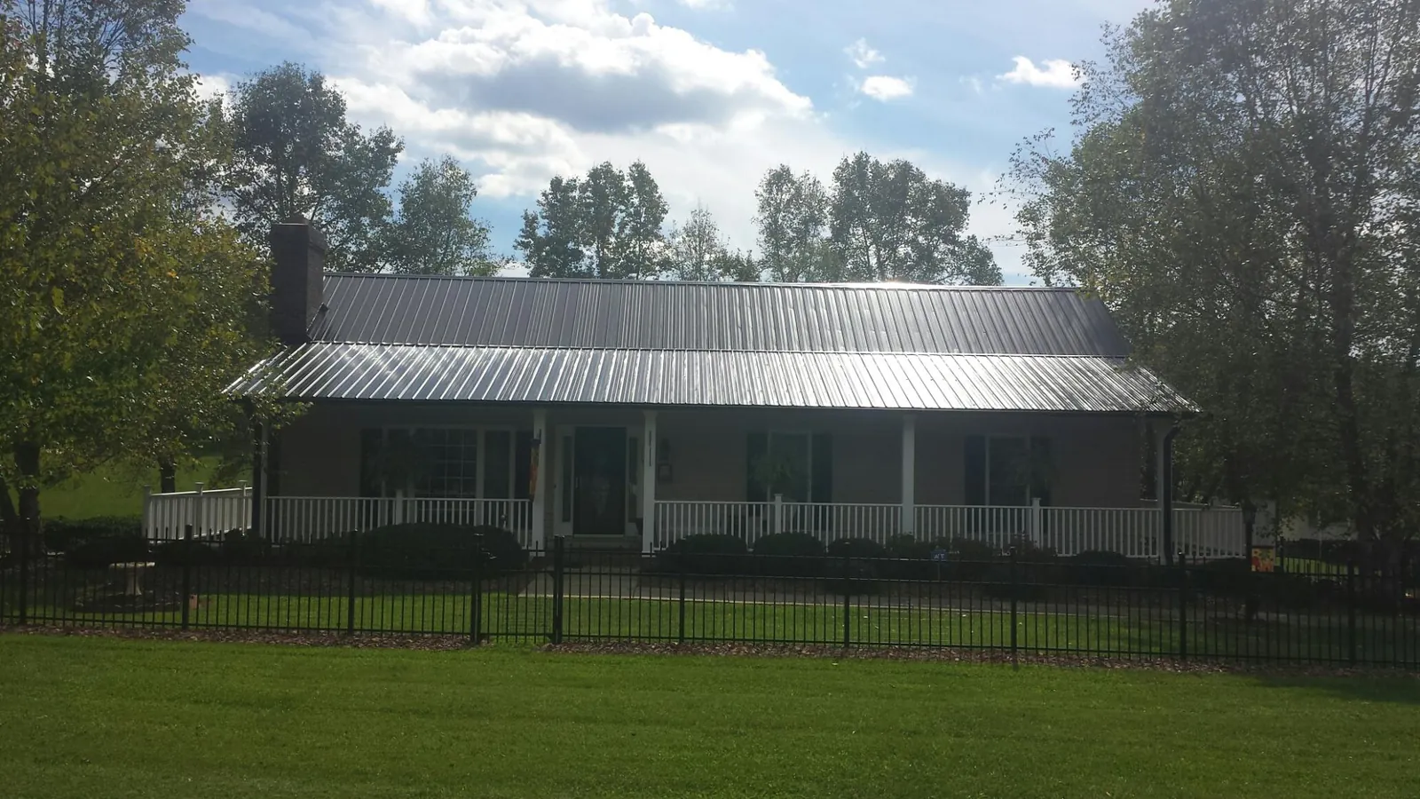 Gray metal roof on a brick ranch with a full width front porch — Gutter Guard Installation work by our crew in Mount Sterling
