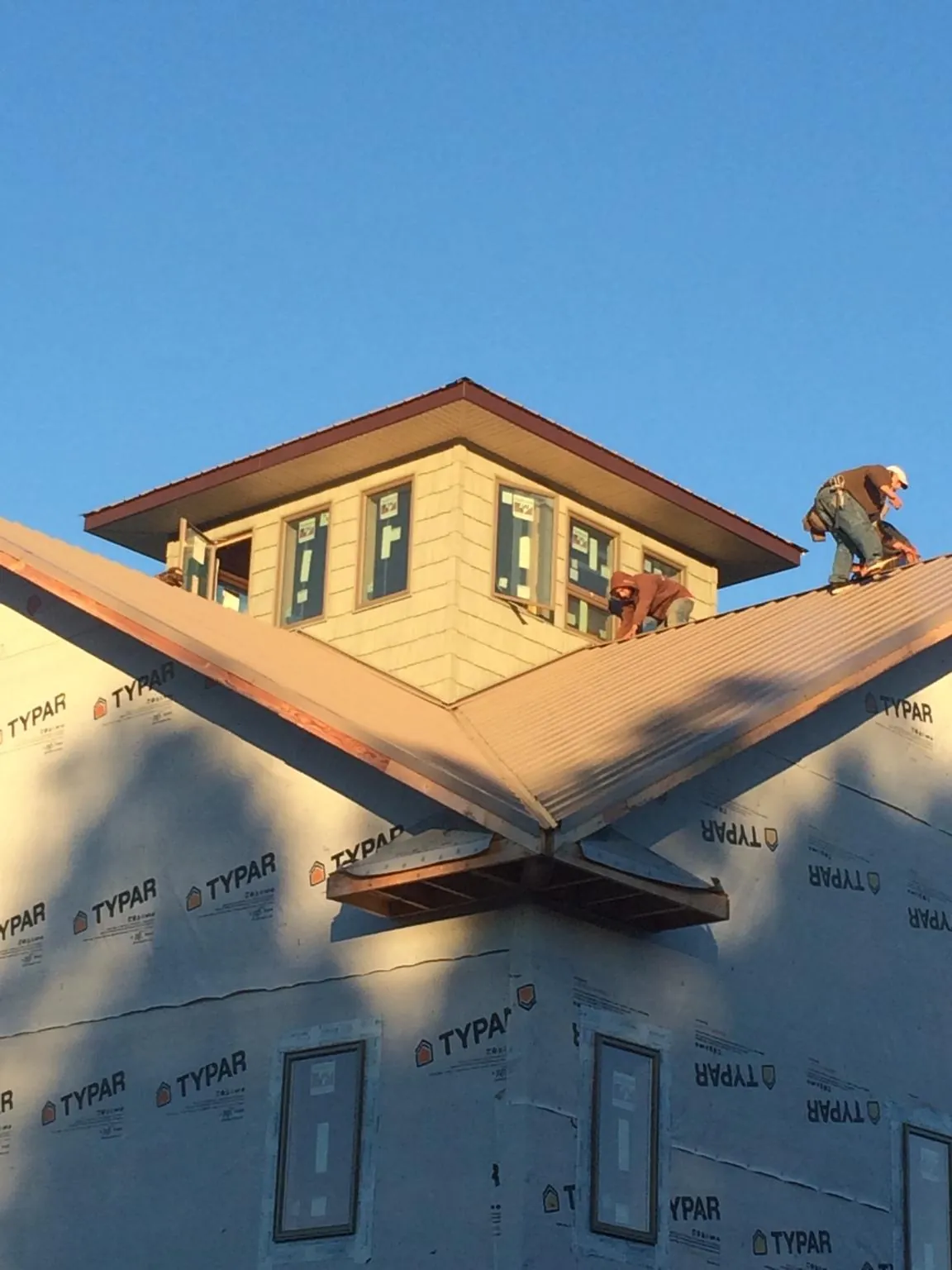 Roofers working around a rooftop cupola on a new metal roof at sunset — Roof Waterproofing in Mount Sterling by Roofing Brothers